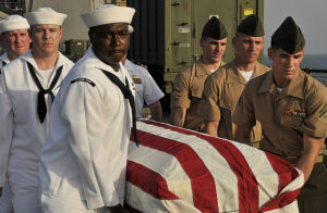 U.S. Navy sailors and Marines carry a casket during a burial at sea ceremony for three U.S. Navy veterans aboard amphibious dock landing ship USS Whidbey Island. Whidbey Island is deployed as part of the Bataan Amphibious Ready Group, supporting maritime security operations and theater security cooperation efforts in the U.S. 5th Fleet area of responsibility. (Photo by Petty Officer 3rd Class Desiree D. Green)