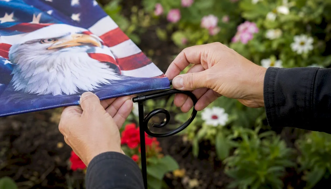 Hands fitting flag sleeve onto garden stake
