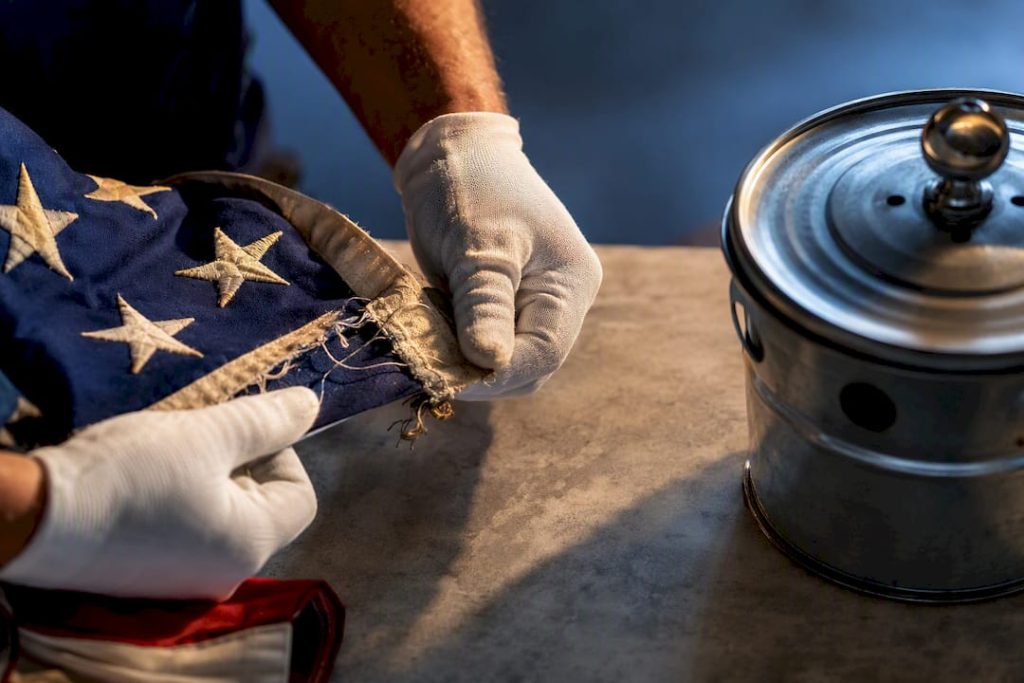 Hands inspecting a worn flag textile