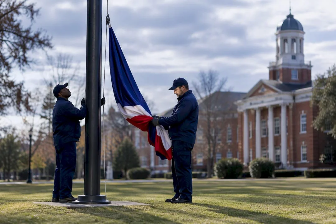 Staff lowering a flag on a university campus